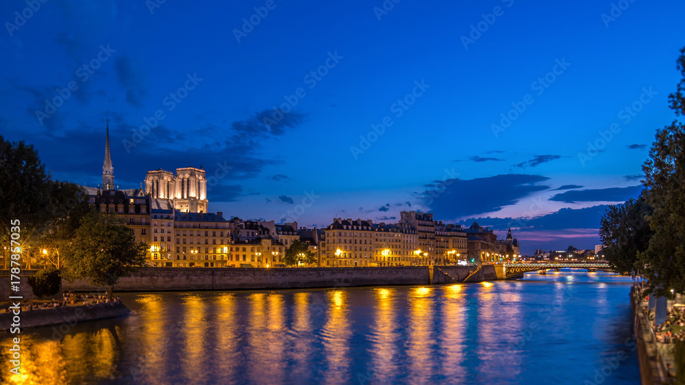 Fototapeta premium Le Pont D'Arcole bridge after sunset with people and boats day to night timelapse, Paris, France, Europe
