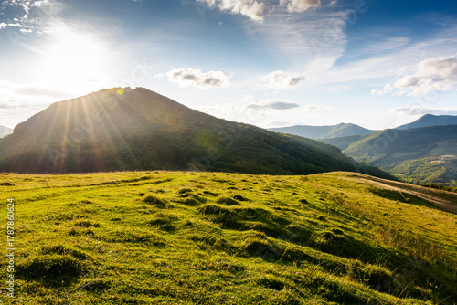 beautiful countryside at sunset. wonderful summertime landscape in mountains in evening light. scenic view of grassy field and rolling hills. rural scenery storytelling image under the rainbow