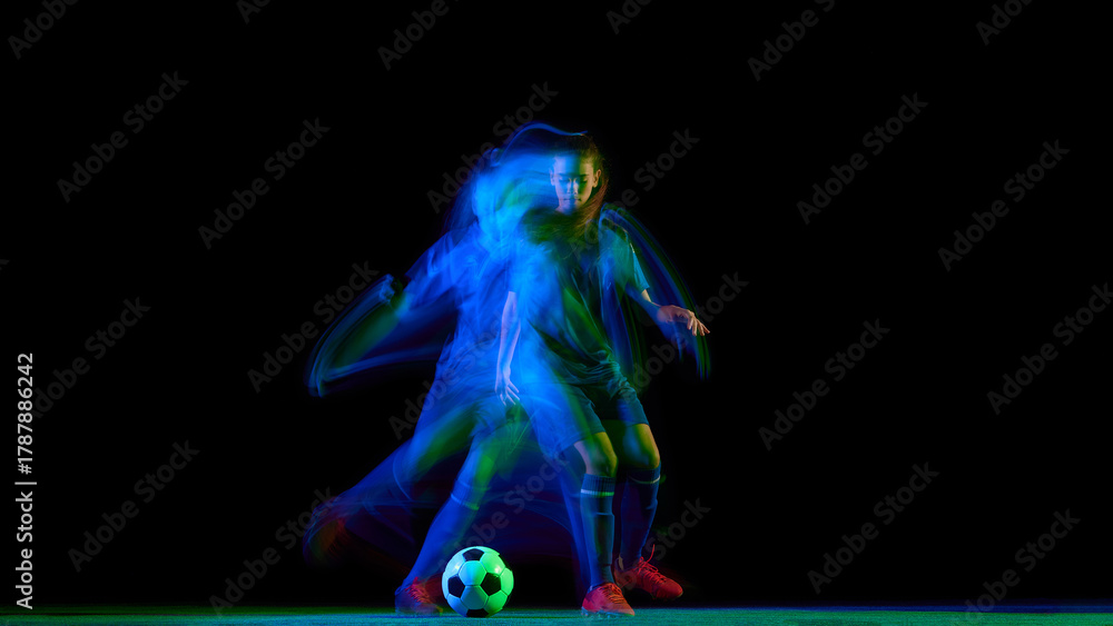 Obraz premium Female soccer player dribbling ball in green and blue motion trail. Concept of coordination, agility drills, sport advertising visuals, and athletic performance promotion.