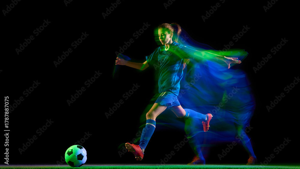 Obraz premium Female soccer player kicking ball in glowing teal and green motion blur. Concept of energy, body in motion, sport performance visuals, fitness campaigns, and brand promotion.