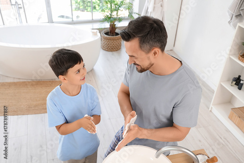 Happy father and his little son with shaving foam in bathroom