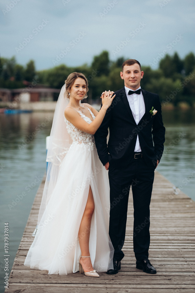 Naklejka premium young couple, the bride and groom, walking along a pier