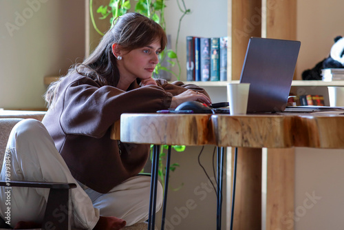 a young girl is working on a laptop, a homely cozy atmosphere