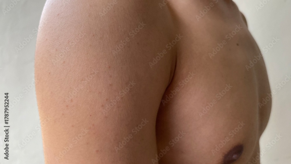 Naklejka premium shoulder and upper chest of a shirtless man against a plain background