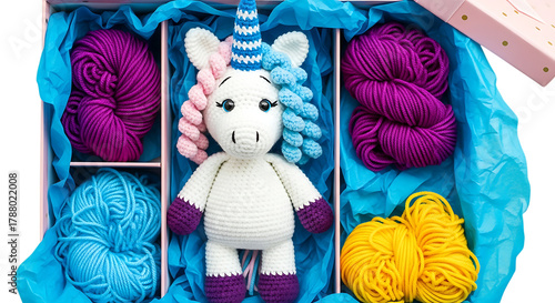 Handmade crochet unicorn toy and colorful yarn skeins in a gift box