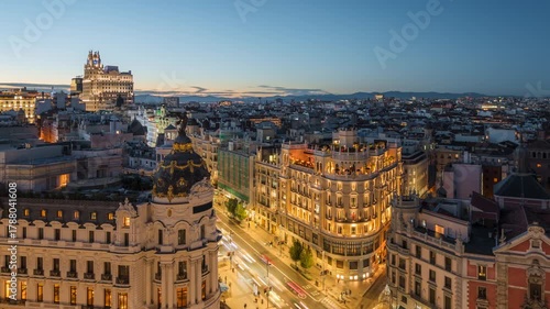Day to night timelapse showing historic buildings and traffic on Gran Via street in Madrid, Spain, zooming out. 