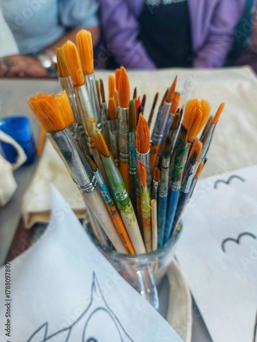 Artist's brushes in a glass jar,drawings on paper.