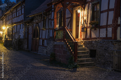 Fototapeta Naklejka Na Ścianę i Meble -  A small, romantic alley in the old town of Idstein in the Taunus region of Hesse, illuminated by streetlights in the evening.