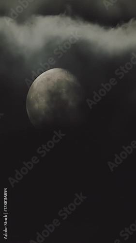 Eerie moonlight piercing through dark, mysterious clouds moving across the night sky