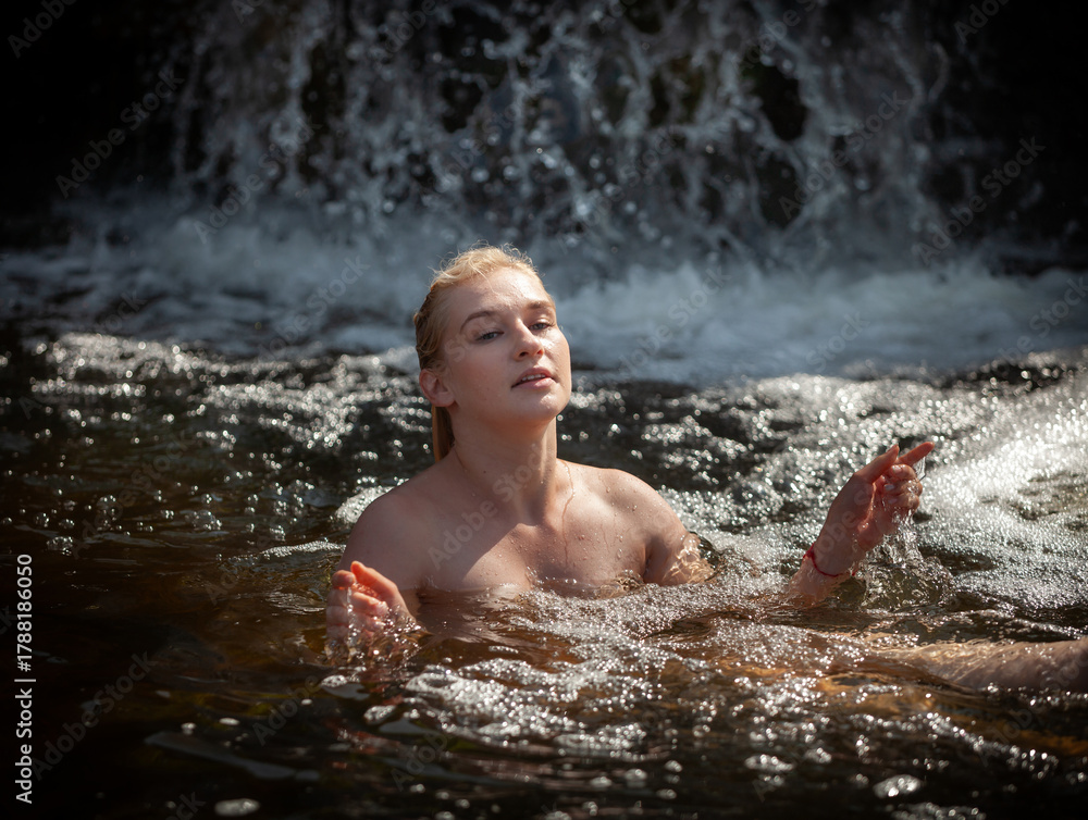 Fototapeta premium Blonde woman enjoying a refreshing swim in a natural waterfall