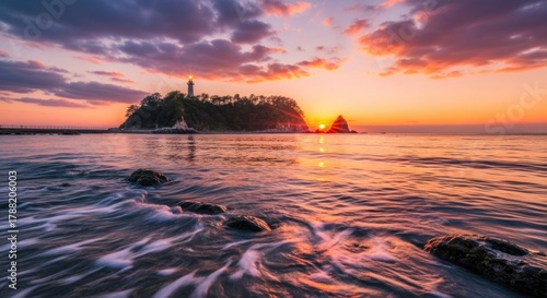 Lighthouse on island at sunset with colorful clouds reflecting in water