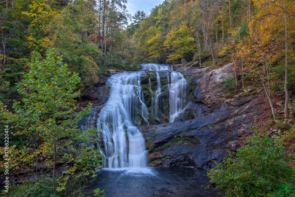 Obraz premium Bald River Falls flows peacefully through vibrant autumn trees near Tellico Plains in East Tennessee during a sunny day