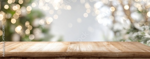 Light wooden tabletop with blurred golden bokeh and green foliage in the background, offering copy space and perfect for Christmas designs and festive marketing