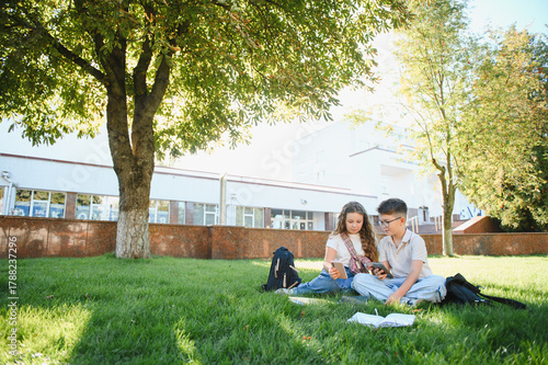 Students using smartphones and studying outdoors on campus