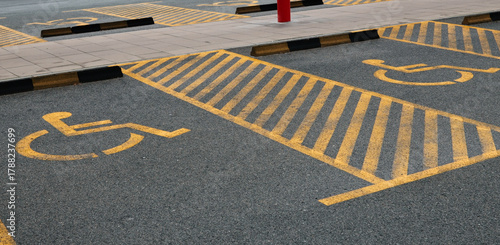 Yellow markings designating accessible parking spots on asphalt surface. The concept represents accessibility, inclusion, and organized infrastructure