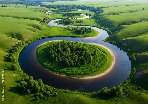 Fototapeta Naklejka Na Ścianę i Meble -  Aerial view of a winding river flowing through lush green rolling hills and meadows in summer