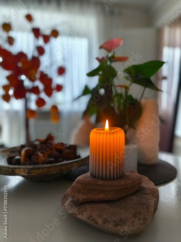 Photography Warm candle flame glowing in a serene autumn still life, surrounded by stones, foliage and soft daylight in a peaceful home setting