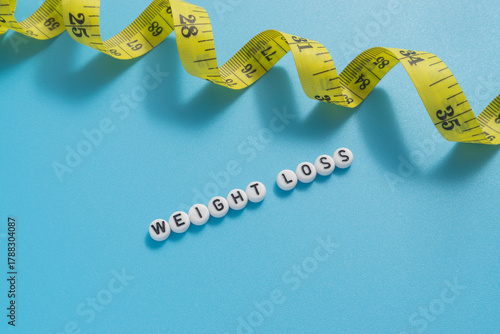 Yellow tape measure with text Weight Loss on light blue background