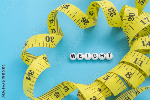 Yellow tape measure with text Weight on light blue background