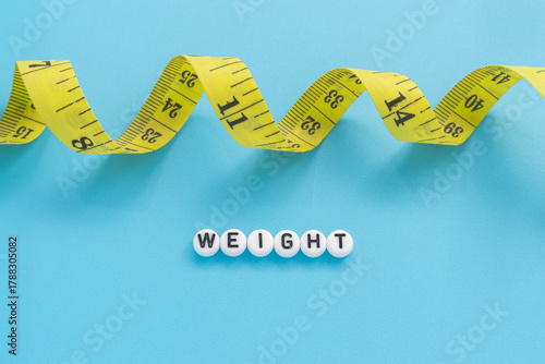 Yellow tape measure with text Weight on light blue background