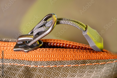 Orange zipper with metallic pull cord, macro close-up