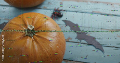Showing large orange pumpkin sitting on left pale blue planks, with bat cutout, spider, glitch band