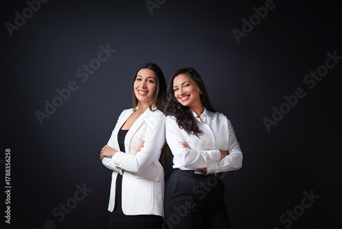 Portrait of two business people. portrait of two young successful business women smiling with joy while standing against neutral background.