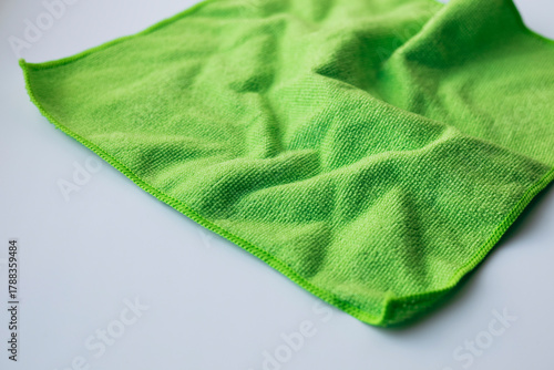 Green microfiber cloth on white background, cleaning concept.