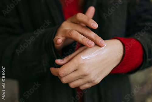 Person applying nourishing hand cream to protect skin from dryness.