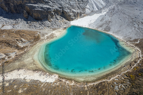 Turquoise alpine lake nestled among dramatic snow-capped mountains. A serene trekking destination in Yading Nature Reserve, Daocheng.