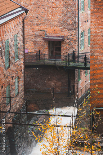 Waterfall cascading near historic industrial building in Mölndal, Sweden, surrounded by autumn colors