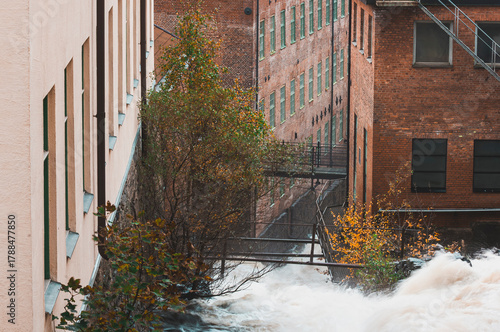 Waterfall flowing near historic industrial building in Mölndal, Sweden, capturing nature's beauty in an urban setting