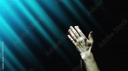 A human clasps his hands in prayer, enveloped in blue divine light. 4K concept slow motion video 60 fps.