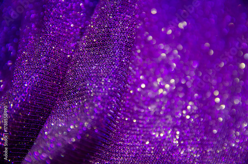 Purple shiny background. Fabric screensaver. Festive decoration. Light and bokeh. 
