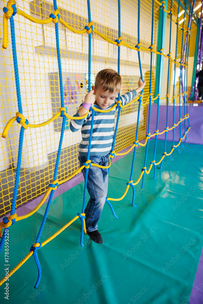 Fototapeta premium Child Enjoying Rope Climbing Adventure in Indoor Playground