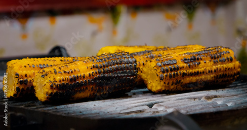 Foto Street vendor grilling corn on the cob over sizzling hot plate, showcasing tradi