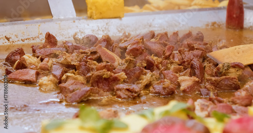Fototapeta Naklejka Na Ścianę i Meble -  Small pieces of meat cooking on a hot plate, releasing steam and juices, a typical street food scene