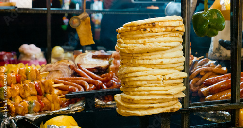 Tableau sur toile Sizzling grilled meat and pita bread at vibrant street market, revealing local c