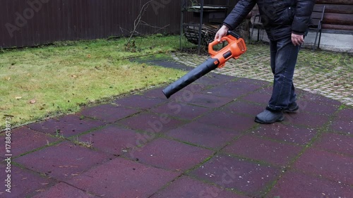 Cordless leaf blower clearing leaves from rubber play surface, front view. High quality 4k footage