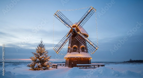 Wallpaper Mural Whisking a festive glow across the serene winter landscape, a charming snow-covered windmill stands adorned with twinkling lights beside a decorated Christmas tree Torontodigital.ca