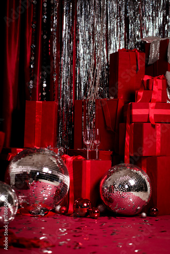 Festive red background with gift boxes, disco balls and sparkling tinsel