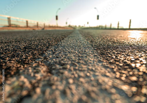 ground-level shot of a close-up of a paved motorway with a white dividing line in the middle, illuminated by the warm light of dawn