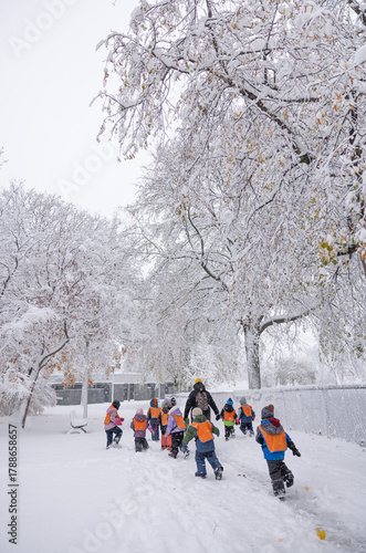 Éducatrice et enfants au parc, enfants jouent dans la neige, jour, vertical