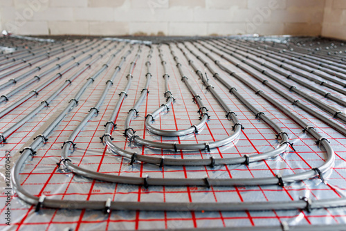 Radiant floor heating pipe installation in modern building,Close-up view of plastic pipes for radiant underfloor heating system installed on insulation layer, energy-efficient home construction.