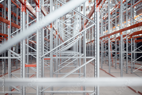 Close-up view of industrial metal shelving racks in a warehouse or factory. The steel structure with orange beams and metal efficient storage system. Logistics industrial design concepts