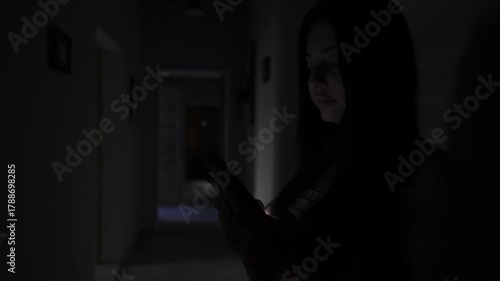 Woman secretly texting a lover in a dark hallway, hidden relationship and cheating
