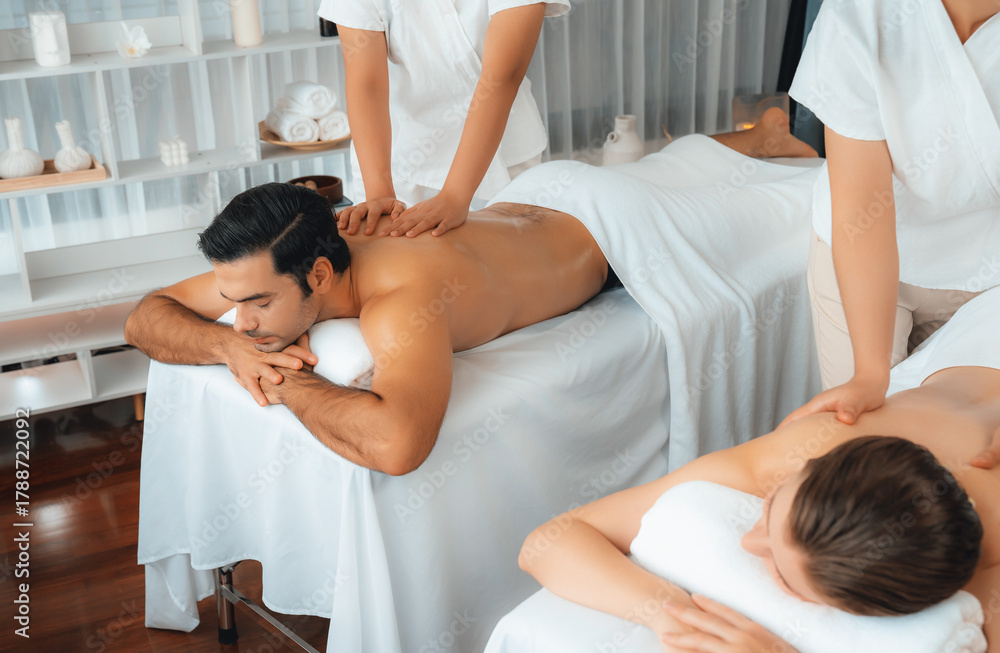 Fototapeta premium Caucasian couple customer enjoying relaxing anti-stress spa massage and pampering with beauty skin recreation leisure in day light ambient salon spa at luxury resort or hotel. Quiescent