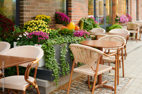 charming outdoor cafe featuring wooden tables surrounded by vibrant potted plants on cobblestone walkway. inviting seating area perfect for al fresco dining or relaxed coffee breaks.