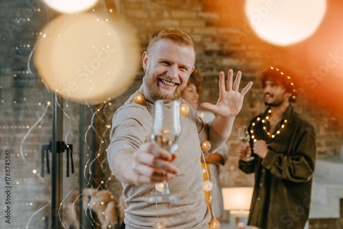 A group of friends dancing with raising glasses of champagne on the Happy New Year party