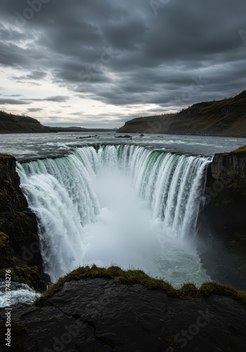 A majestic, wide, and powerful horseshoe waterfall cascades over dark rock formations, generating heavy mist and spray in the rugged landscape, rock, river, flow